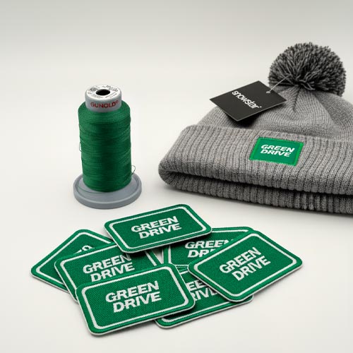 Bonnet Pompon Contrast GreenDrive avec écusson brodé, fil à broder et écussons textiles réalisés par Textile Print.