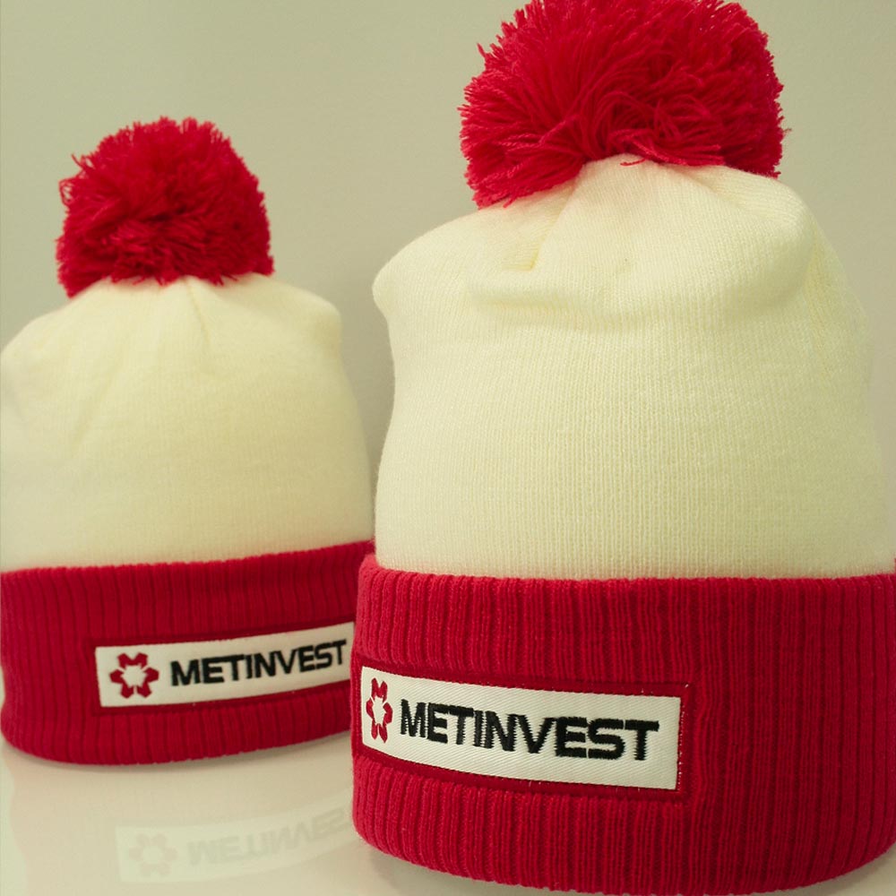 Deux bonnets METINVEST blanc et rouge avec écusson brodé, posés côte à côte.