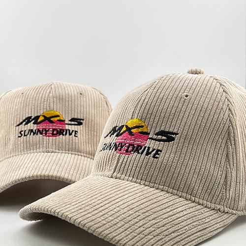 Deux casquettes en velours beige avec broderie Sunny Drive représentant un soleil jaune et rose au-dessus du texte noir