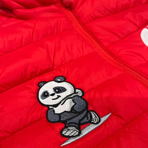 Gros plan sur une broderie de panda sur une doudoune sans manches rouge