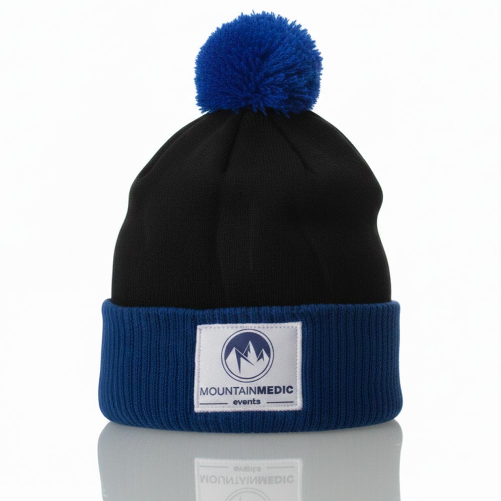 Bonnet MountainMedic noir et bleu avec pompon assorti et écusson brodé, présenté sur fond clair.