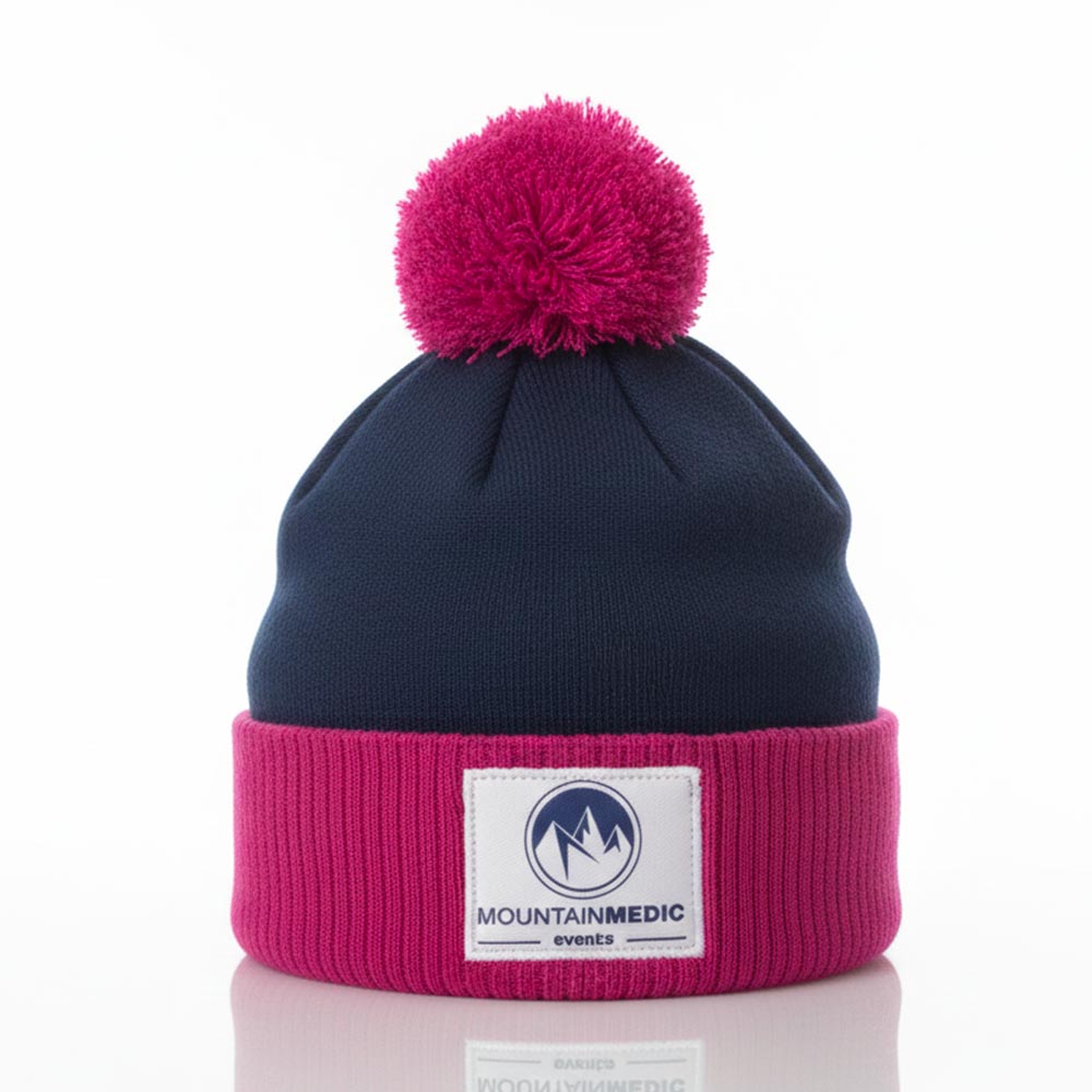 Bonnet MountainMedic marine et rose avec pompon rose et écusson brodé.