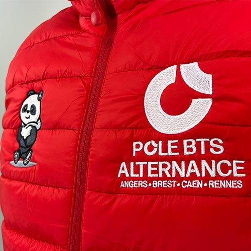 Vue rapprochée d’une doudoune rouge avec broderies du logo Pôle BTS Alternance et d’un panda.
