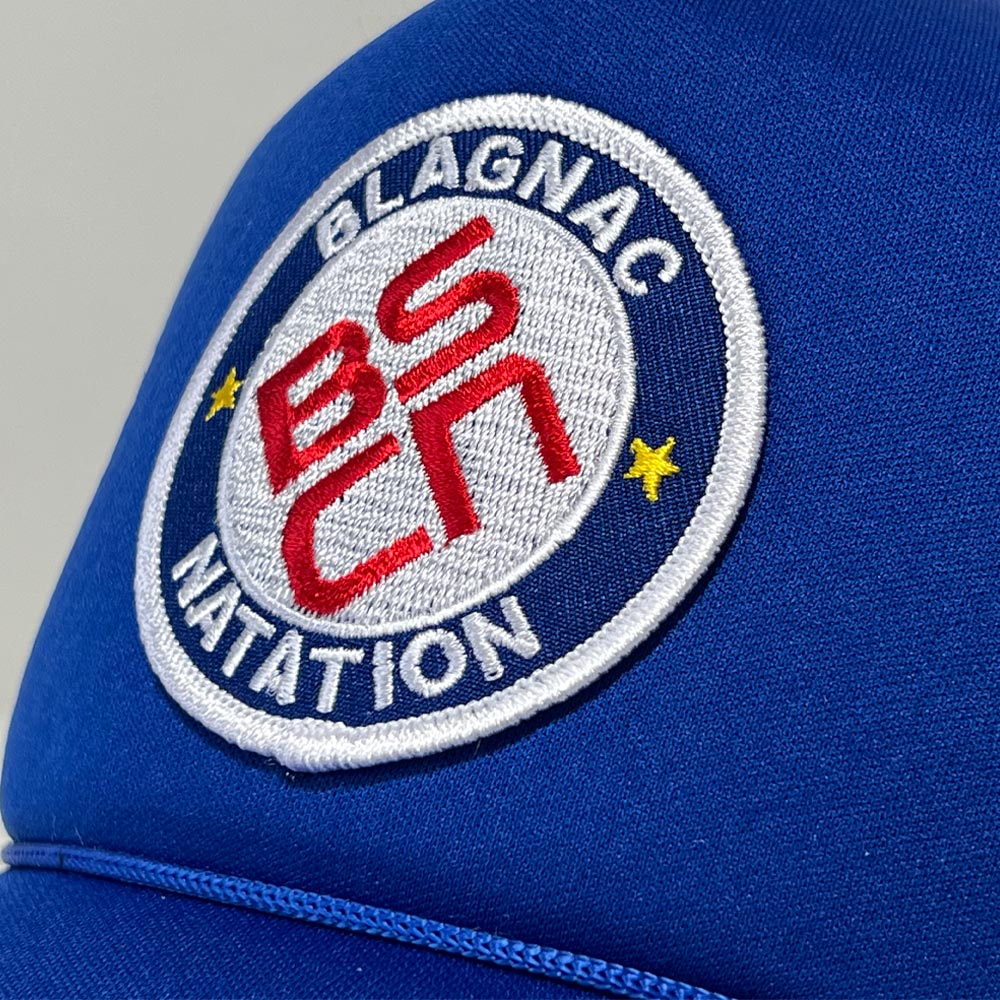 Gros plan sur l’écusson brodé BSCN du club Blagnac Natation sur casquette personnalisée.