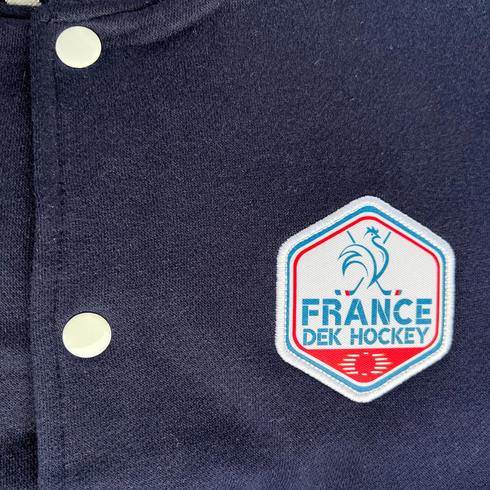 Détail de l’écusson France DEK Hockey brodé sur une veste varsity bleu marine.