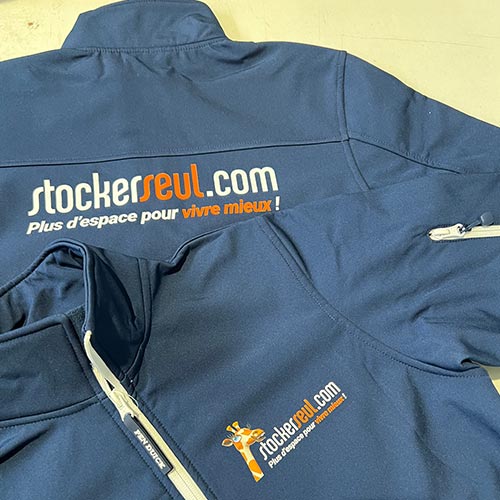 Veste softshell personnalisée bleu marine avec logos imprimés sur la poitrine et le dos.