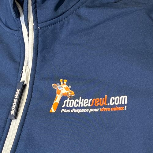 Gros plan sur le logo imprimé sur la poitrine d’une veste softshell bleu marine.