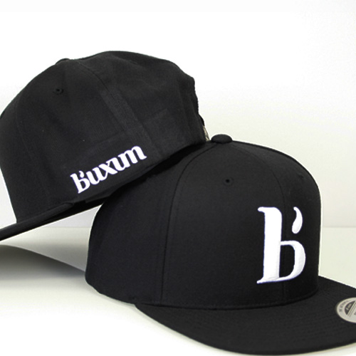Duo de casquettes Buxum noires montrant le logo frontal en 3D et le lettrage brodé sur le panneau latéral.