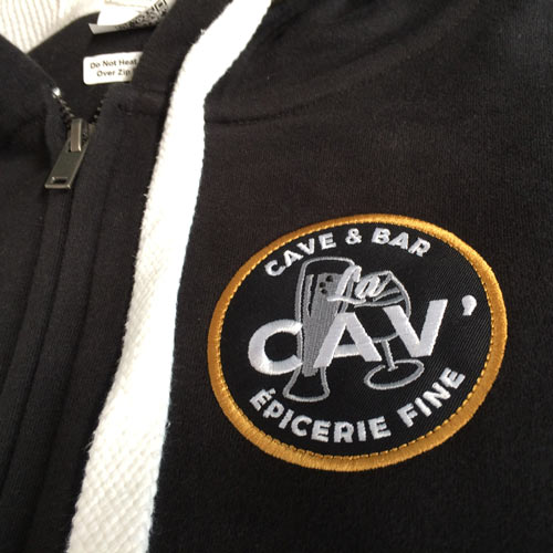 Veste à capuche noire personnalisée avec écusson brodé La Cav' épicerie fine sur la poitrine
