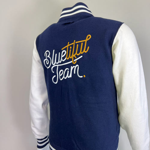 Veste teddy bleu marine et blanche brodée dans le dos avec le texte Bluetiful Team